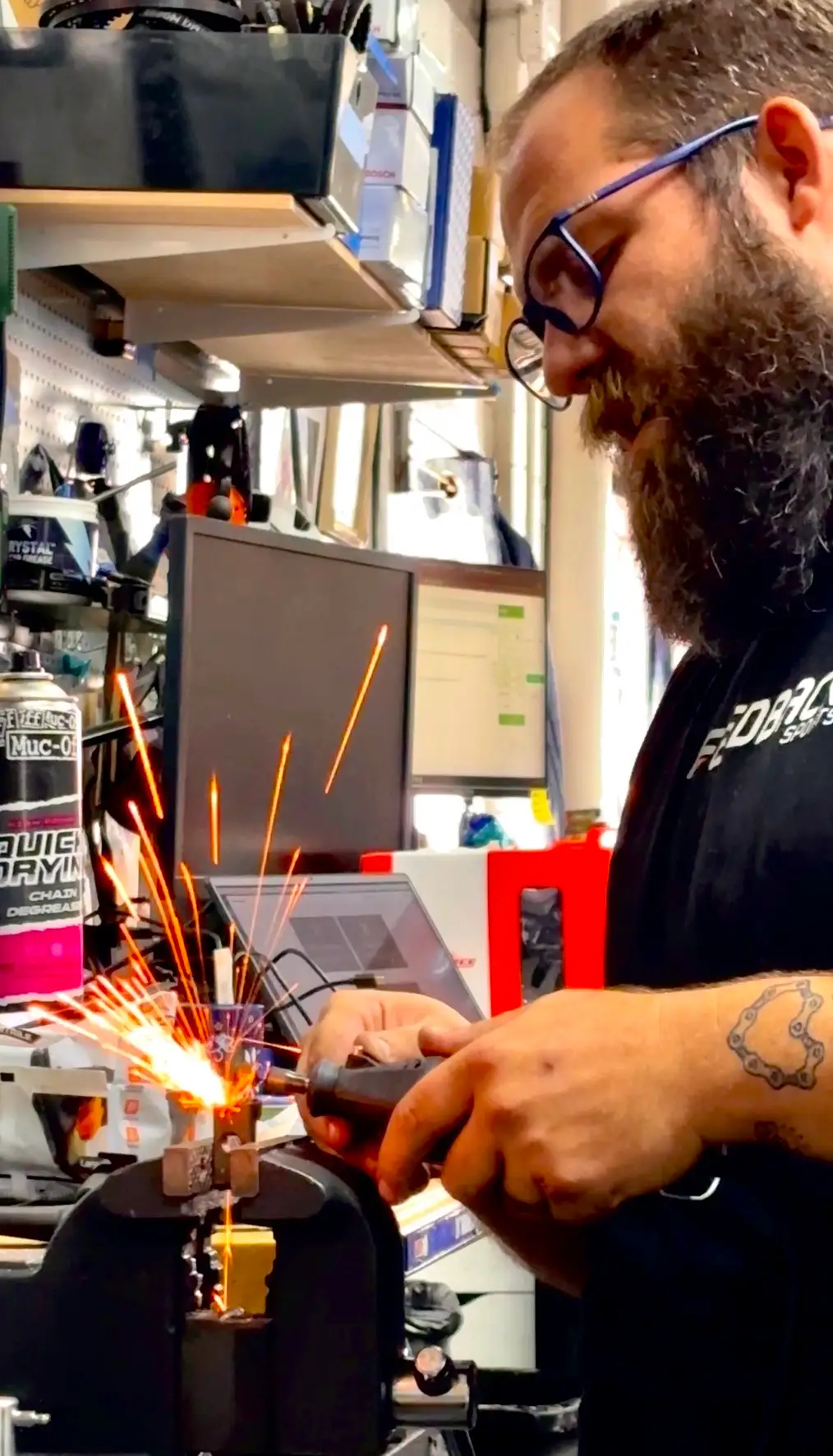 A Hardt Family Cyclery technician grinding at the workbench, sparks flying